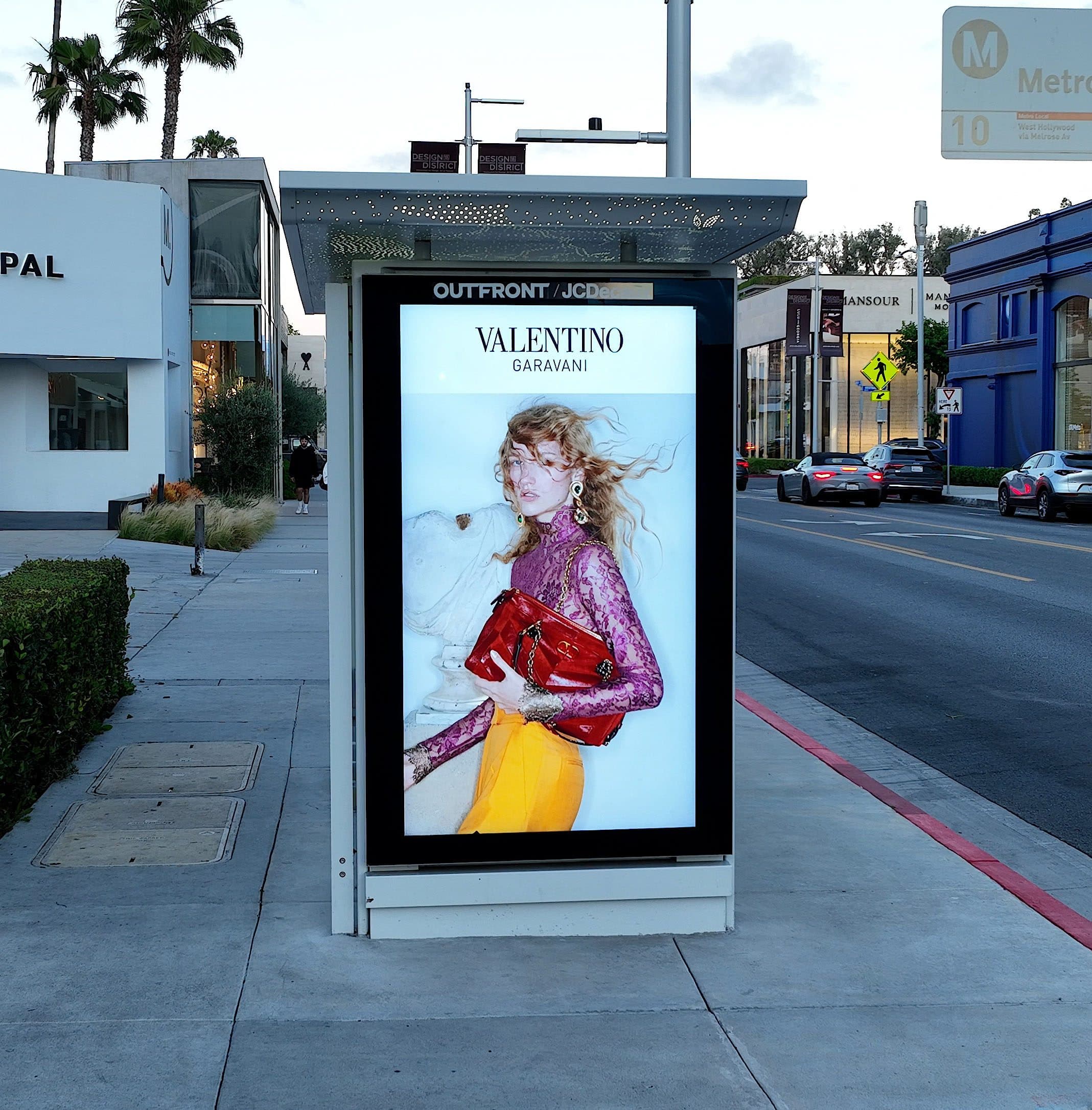 Valentino Garavani — digital transit shelter on a palm-lined boulevard